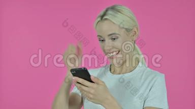 年轻女子在智能手机、粉红背景下取得成功